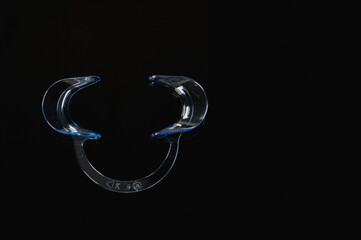 Plastic retractor in dental clinic isolated in black