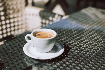 Cup of black coffee on a table in a street cafe.
