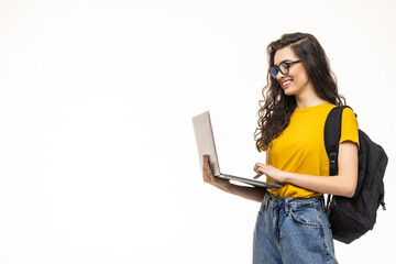 College student girl on gray background, smiling at camera, pressing laptop to chest, wearing...