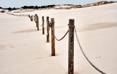 Wooden stakes with rope and ropes in the sand of the mighty shifting sand dune of Leba, Poland