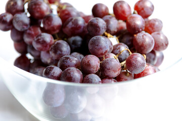 bunch of grapes close up in glass bowl on white background
