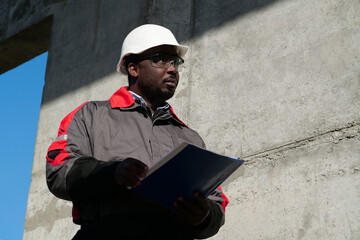 African american worker stands at construction site with work papers