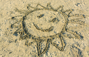 Child's drawing of smiling sun on yellow sand