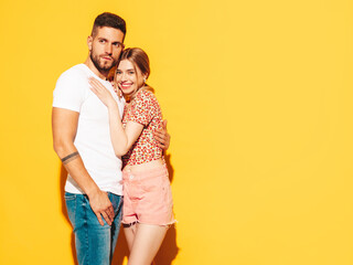 Sexy smiling beautiful woman and her handsome boyfriend. Happy cheerful family having tender moments near yellow wall in studio. Pure cheerful models hugging. Embracing each other