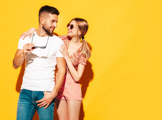 Sexy smiling beautiful woman and her handsome boyfriend. Happy cheerful family having tender moments near yellow wall in studio. Pure cheerful models hugging. Embracing each other