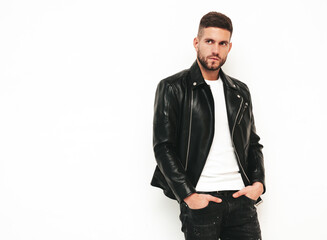 Fototapeta premium Portrait of handsome confident model. Sexy stylish man dressed in biker leather jacket and black jeans. Fashion hipster male isolated on white in studio