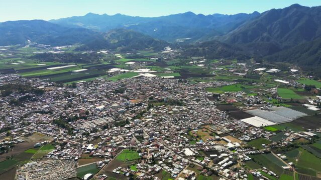 Aerial orbit view of the Constanza town in a valley surrounded by mountains. Agriculture of Dominican Republic, high production of vegetables and fruits