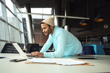 Male in hat typing on laptop in the office