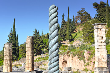 Serpent Column of Plataea or Delphi Tripod in front of the Temple of Apollo in Delphi, Greece, an ancient sanctuary that grew rich as seat of oracle that was consulted on important decisions