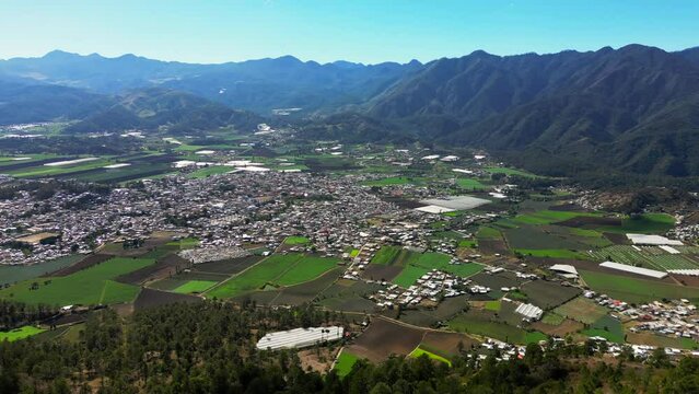 Aerial panoramic view of the Constanza town in a valley surrounded by mountains and agriculture fields. High production of vegetables and fruits in Dominican Republic