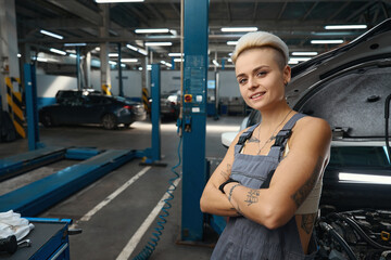 Fototapeta na wymiar Cute woman auto repairman stands at workplace at working box