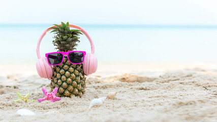Summer in the party.  Hipster Pineapple Fashion in sunglass and listen music with sunblock and sandal on the sand beach beautiful blue sky background.  Fashion Summer Vacation Concept
