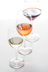 Three glasses of different wines in a row, against a white background.
