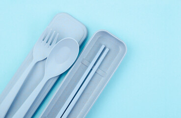 The Plastic spoons, forks and chopsticks kit set on blue background.