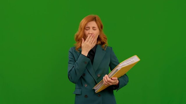 Tired business woman while standing In front of green screen background with big folder in her hands. Exhausted pretty woman from long hours working. E otion and feelings concept.