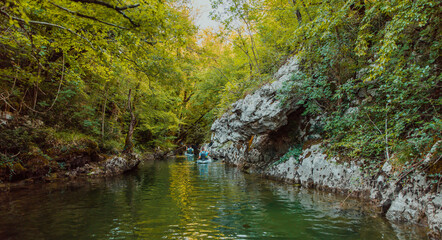 Fototapeta premium A group of friends enjoying having fun and kayaking while exploring the calm river, surrounding forest and large natural river canyons