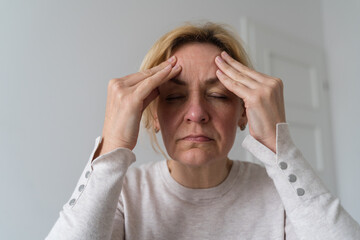 Mature woman has headache at home. Menopause or depression concept