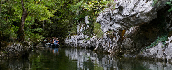 A group of friends enjoying having fun and kayaking while exploring the calm river, surrounding forest and large natural river canyons