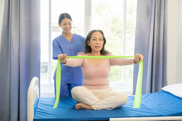 Fototapeta na wymiar Happy senior woman exercising at home with muscle physiotherapist Retired elderly woman stretching arms and legs at home with personal trainer