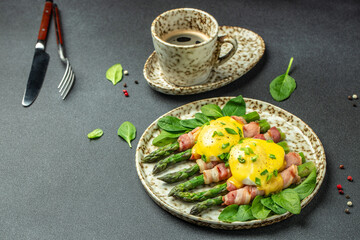 Fototapeta na wymiar Delicious breakfast with eggs Benedict and green asparagus wrapped in grilled bacon and a cup of coffee. banner, menu, recipe place for text, top view