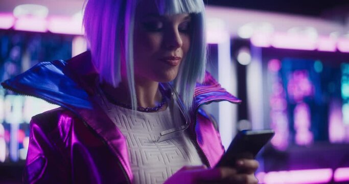 Portrait of a Stylish Cyberpunk Cosplay Girl with Blue Hair Using Smartphone. Young Happy Beautiful Gamer Girl Browsing Internet, Chatting and Shopping Online in a Futuristic Neon Room