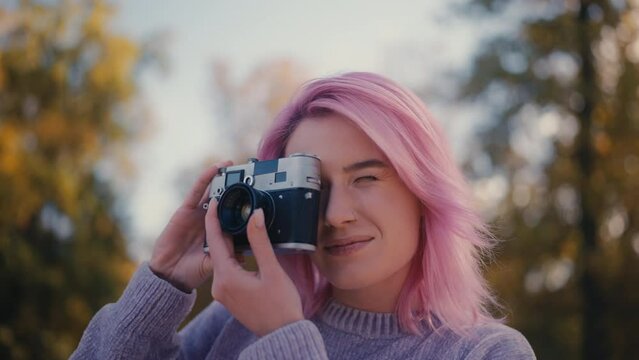 Young woman with pink hair using vintage camera, film photography, hobby