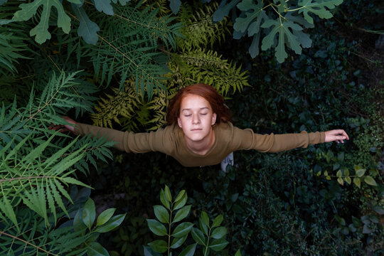 Girl standing with arms outstretched amidst plants
