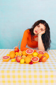 Young woman leaning on elbow with citrus fruits on table