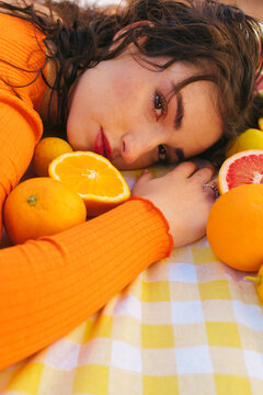 Young woman leaning on table with citrus fruits