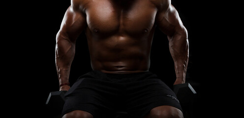 Fototapeta na wymiar Muscular bodybuilder doing exercises with dumbbells on black background