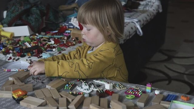 a small child in the playroom plays with toys and sorts through the beads. Boy playing on the couch in a pile of toys