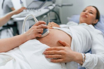 Pregnant woman is lying down in the hospital, doctor does ultrasound