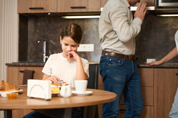 Sad little girl having breakfast in the kitchen
