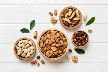 mixed nuts in wooden bowl. Mix of various nuts on colored background. pistachios, cashews, walnuts, hazelnuts, peanuts and brazil nuts