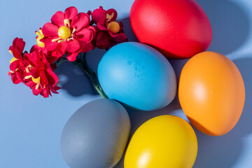 Colorful eggs, symbolizing Easter, on a colorful background and flowers
