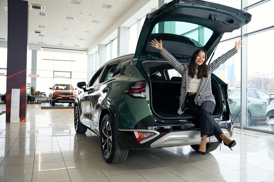 Beautiful young woman rejoices in a new car