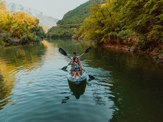 A group of friends enjoying fun and kayaking exploring the calm river, surrounding forest and large natural river canyons during an idyllic sunset.