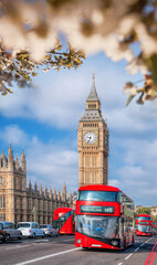 Famous Big Ben with red double decker bus on bridge over Thames river during springtime in London, England, UK