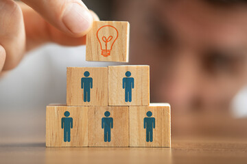 Businessman holding a wooden cube with light bulb on it. Teamwork and employment business concept.