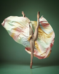 One young adorable professional ballet dancer wearing colorful dress dancing over dark green background. Demonstrating body flexibility © Lustre Art Group 