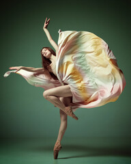 One beautiful adorable, young girl dancing gracefully with with fabric over dark green studio background. Modern ballet with silk dress © Lustre Art Group 