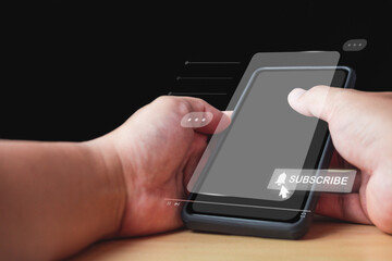 Man holds an unidentified smartphone. Click on subscribe button. Social media concept with copy space.