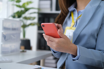 Close up view of businesswoman holding and using smartphone in the office room.