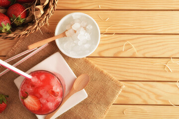 Glass of natural iced strawberry juice on wooden table top