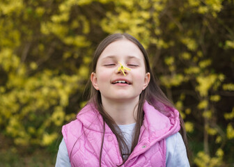 Beautiful girl in a blooming spring park. Girl 8 years old in spring on the background of yellow bushes, flowers and grass. Spring concept