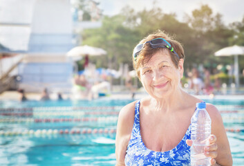 Active healthy senior (elderly) woman (over the age of 50) in sport goggles and with towel and...