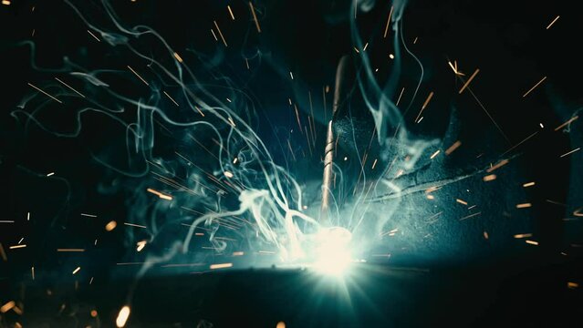 The man is welding. Welding with argon or electrode, using a welding machine. Sparks and flashes fly.