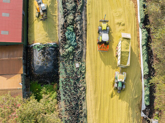 Traktor und Bagger auf einer Maissilage während der Maisernte