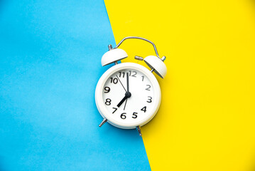 white alarm clock on two tone color yellow and light blue background