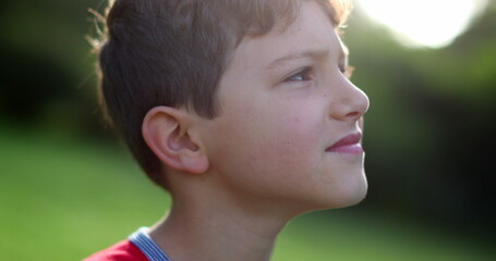 Pensive child face looking at the sky thinking. Contemplative thoughtful young boy kid